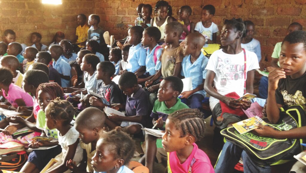 Ett klassrum fullt med barn från Mocambique som sitter och lyssnar på undervisning.