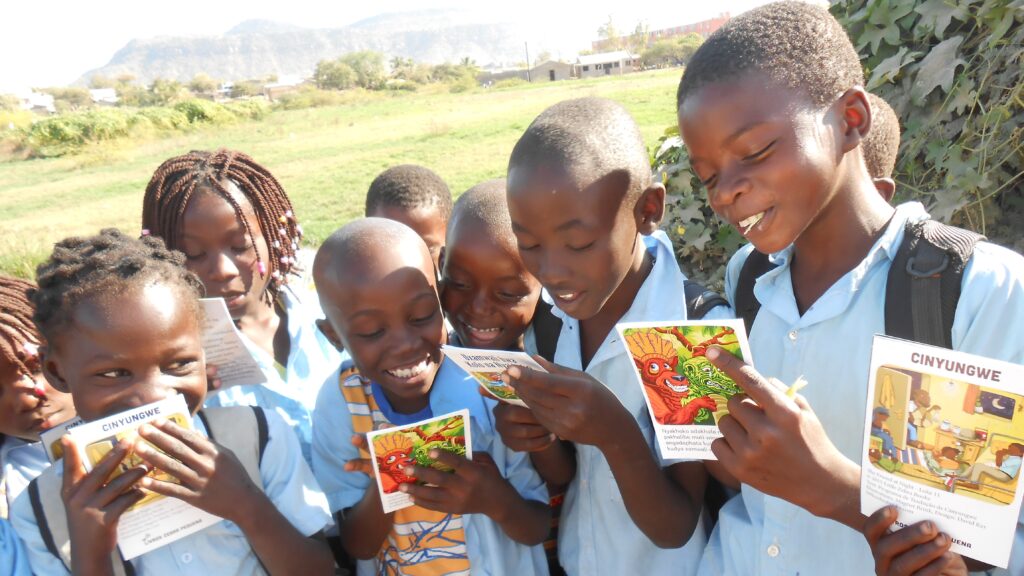 Ett större gäng barn från Mocambique läser färgglada bibelillustrationer.