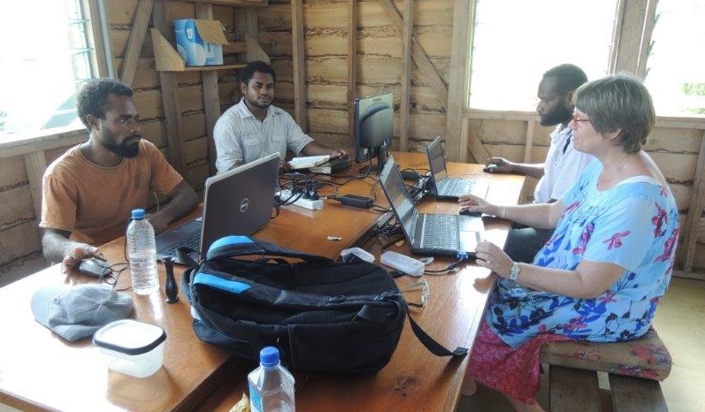 En grupp människor sitter runt ett bord med varsin dator.