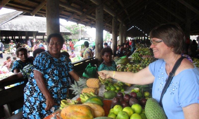 En kvinna köper frukt från ett marknadsstånd.