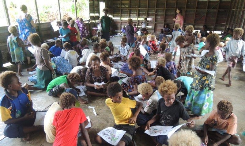 En samling barn sitter på ett jordgolv.