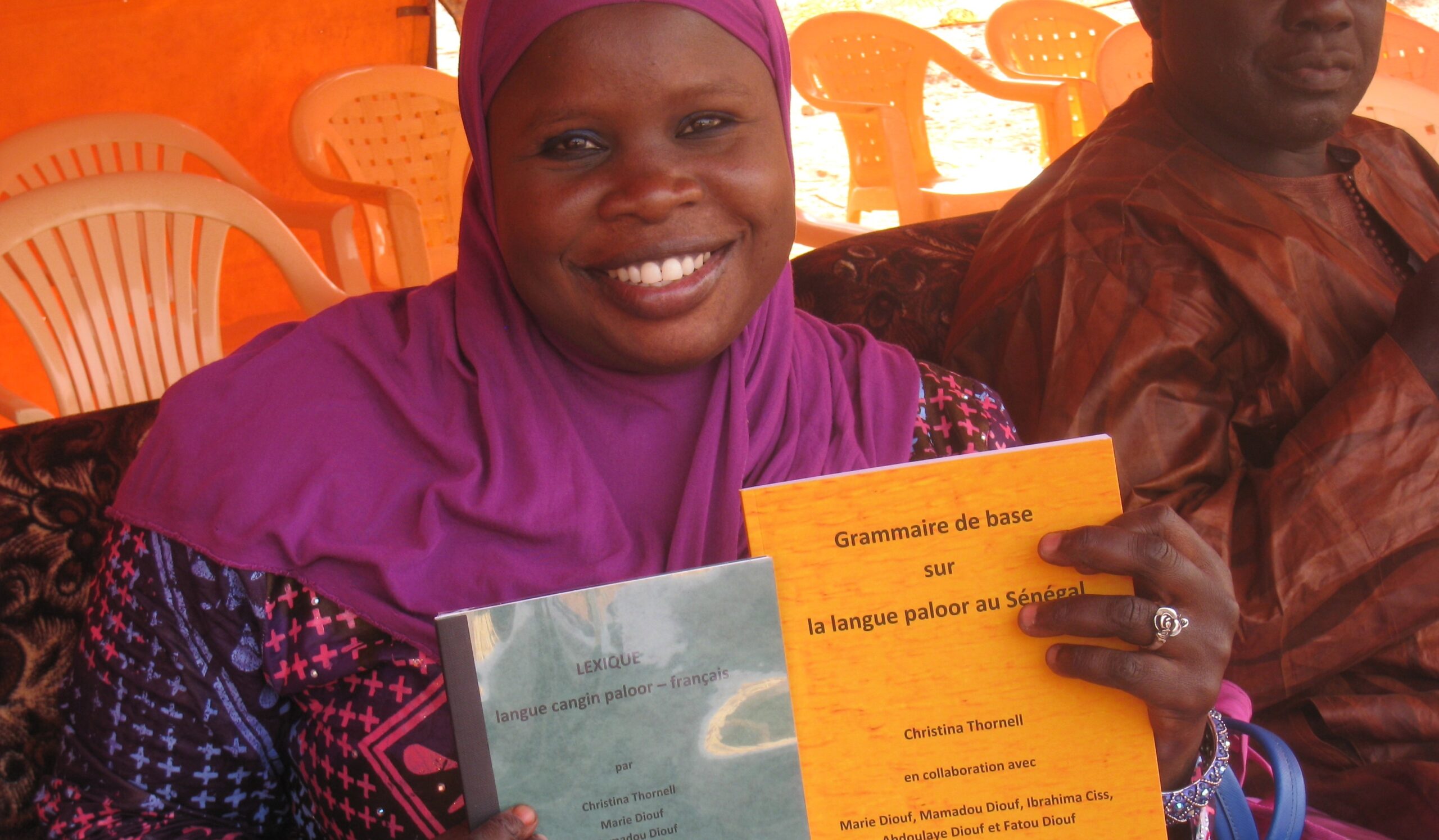 Foto av Marie Diouf som håller upp två språkhäften.