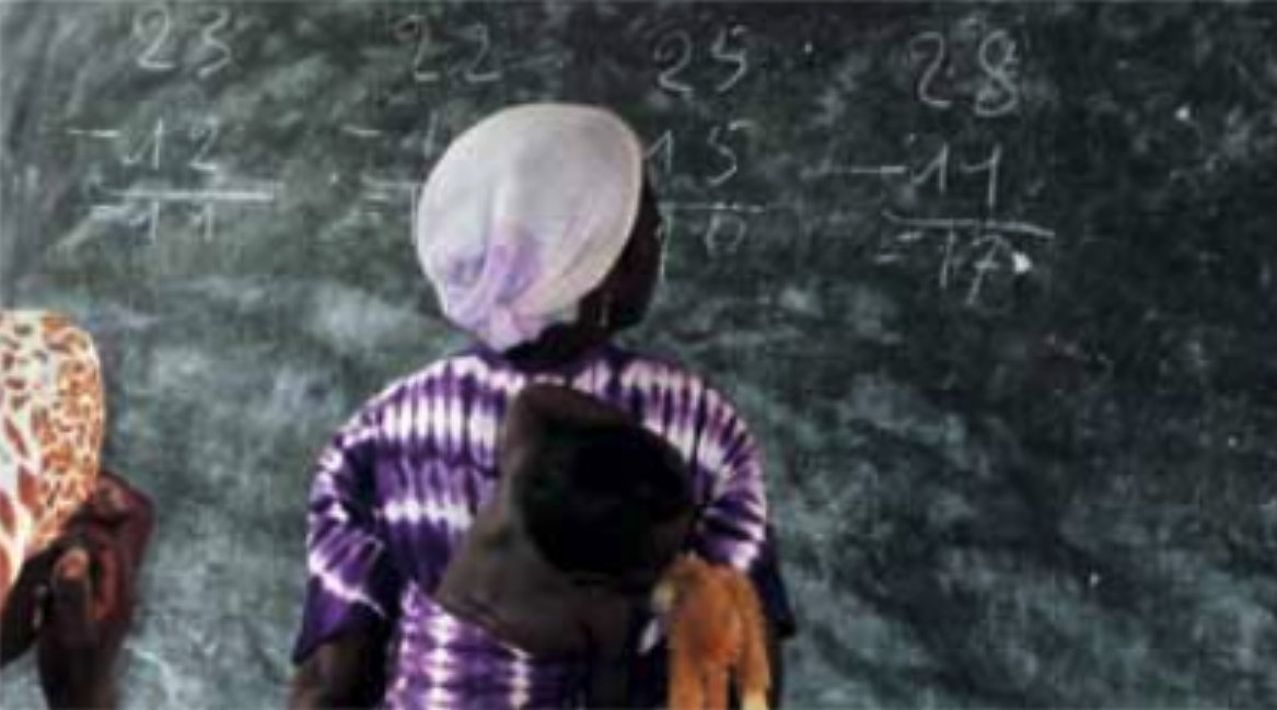 En kvinna står framför en stor griffeltavla.