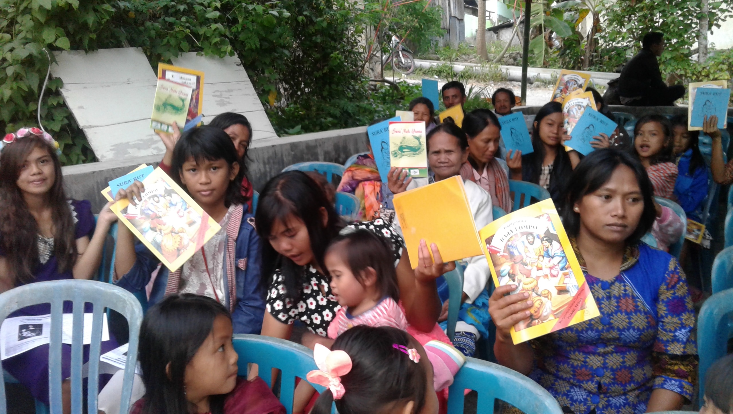 En grupp flickor och kvinnor håller upp läsmaterial.